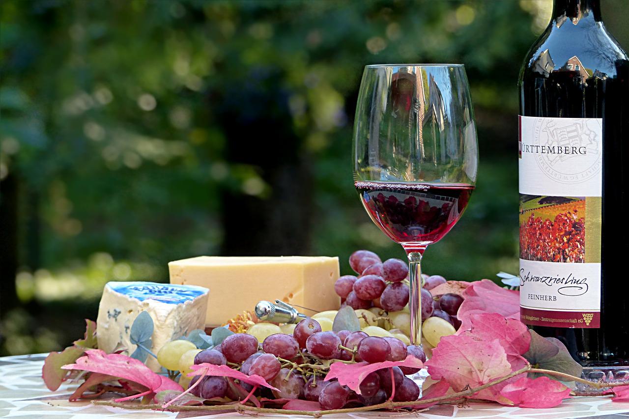 Tavola con bottiglia, calice di vino, uva e formaggi