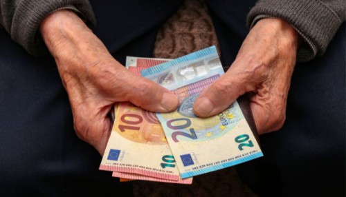 Mani di un anziano che tengono delle banconote